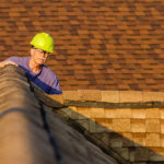 An inspector looks over a residential roof at the peak.